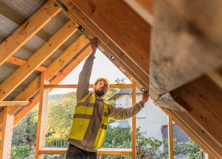 Bauarbeiter steht inmitten eines Dachgebiels, an welchem gerade gebaut wird.