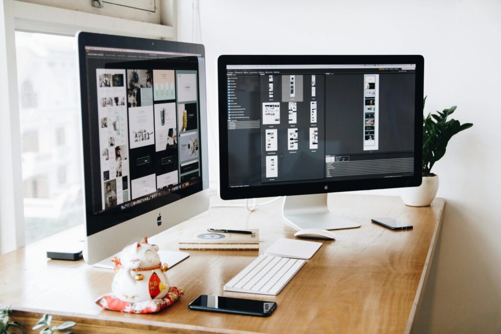 Zwei Imacs Mit Tastatur Und Telefonen Auf Dem Schreibtisch